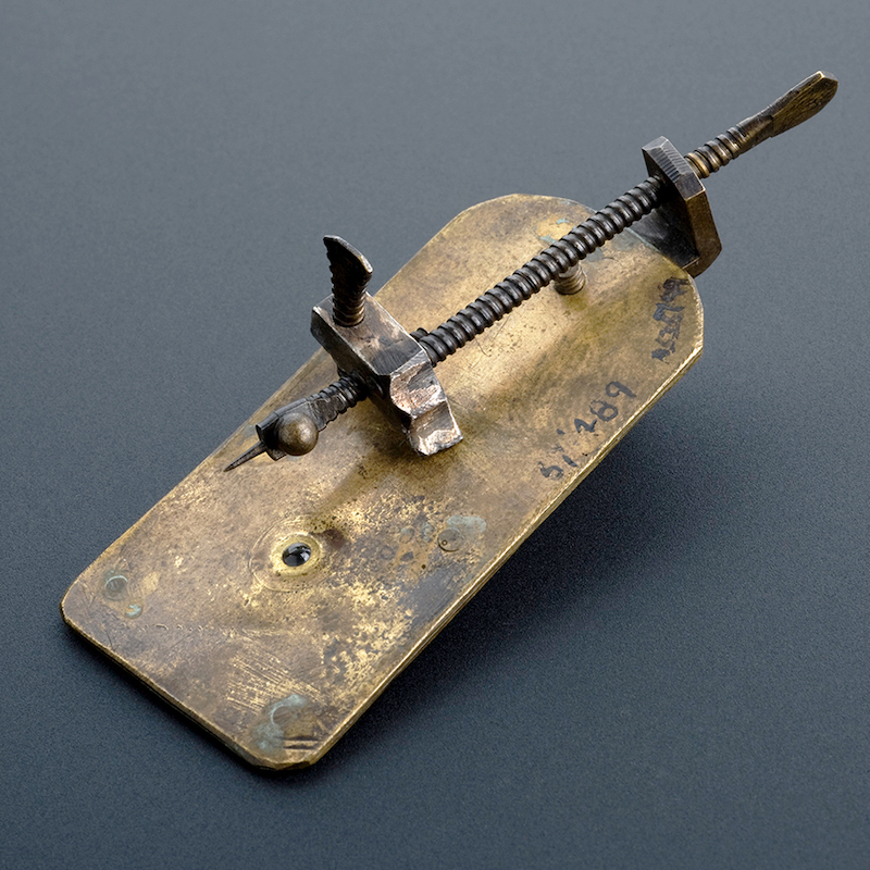 Figure 2: van Leeuwenhoek's simple microscope. On the brass plate is a small magnifying lens mounted and a sharp point that would hold the specimen. Turning the screws would adjust the position and focus.
